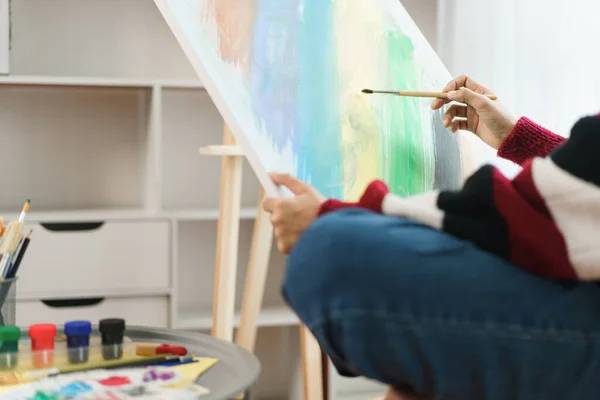 The art concept, Asian female artist sitting on the chair and holding canvas to painting artwork.
