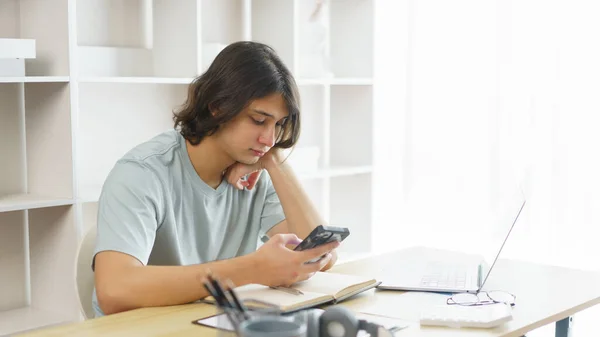Distance education concept, Teen boy using phone to check class schedule of online learning at home.