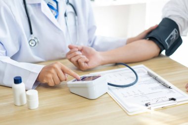 Doktor konsepti olan bir doktoru ziyaret etmek, hastanın kolundaki kan basıncını ölçmek için aracı kullanmak.