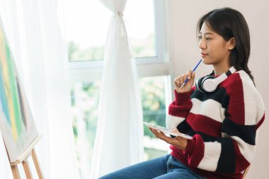 Sanat konsepti, Asyalı kadın ressamın tuvalin önünde oturup sanat eserleri yaratmayı düşünmesi..