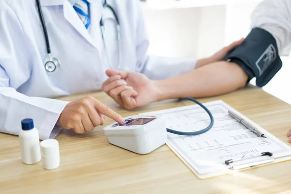 Visiting a doctor concept doctor sitting using the tool to measure blood pressure on the patients arm carefully