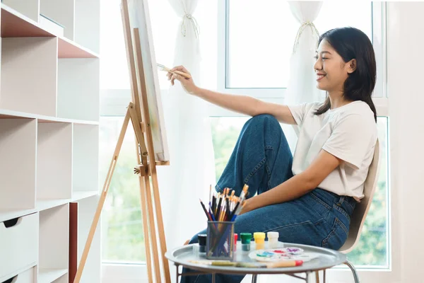 The art concept, Asian female artist using paint brush to painting for create artwork on canvas.