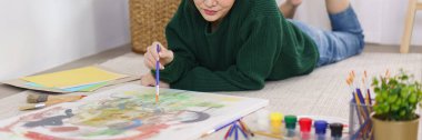 Sanat konsepti, genç Asyalı kadın yerde yatıyor ve sanat şaheserini resmetmeye çalışıyor..
