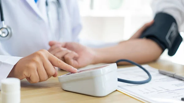 Visiting a doctor concept doctor sitting using the tool to measure blood pressure on the patients arm carefully