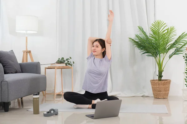 Yoga exercise concept, Young Asian woman stretching arms before workout with yoga training online.