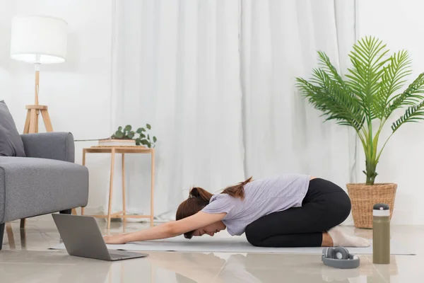 Yoga exercise concept, Asian woman doing yoga with lying in child pose in class online at home.