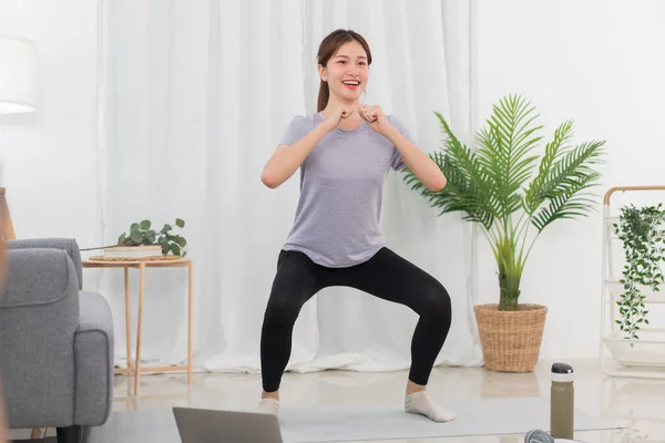 Yoga exercise concept, Young Asian woman doing yoga exercise with tutorial training online at home.