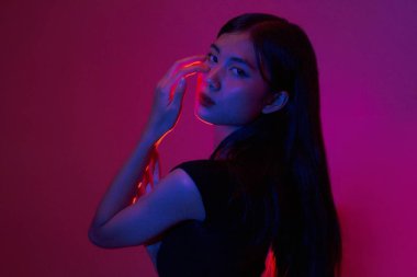 Moda ve güzellik anlayışı. Moda kadını, neon ışıklı arka planda poz vermek için el kullanır..