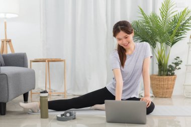 Yoga exercise concept, Young Asian woman doing yoga exercise with tutorial training online at home.