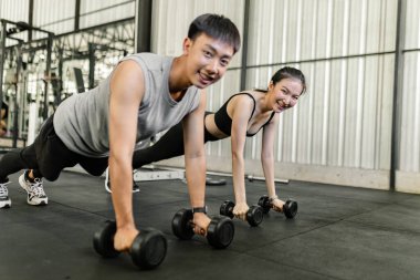 exercise concept the well shaped lady and the muscular man being entertaining having small chat while riding the exercise bike machines.