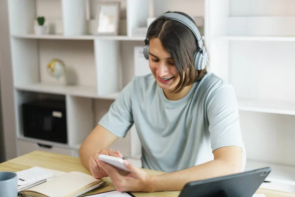 Distance education concept, Teen boy in headphone to listen music and use phone after study online.