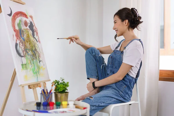 Creative of art concept, Young asian woman holding paintbrush and contemplate about the artwork.