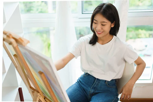 The art concept, Asian female artist use paintbrush to drawing artwork on canvas in art studio.