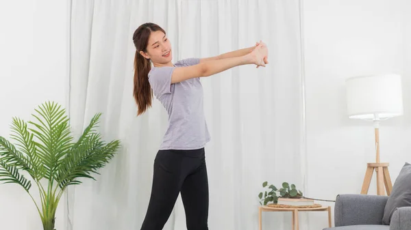 Yoga exercise concept, Asian woman warm up to stretching arms before doing yoga exercise online.