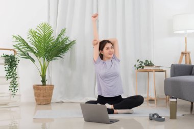 Yoga exercise concept, Young Asian woman stretching arms before workout with yoga training online.