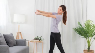 Yoga exercise concept, Asian woman warm up to stretching arms before doing yoga exercise online.