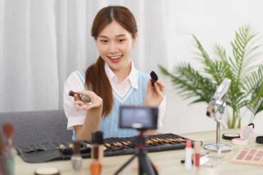 Güzellik blogcusu konsepti, genç Asyalı kadın elinde fırça ve tırnak cilası ile abonelere teftiş yapıyor..