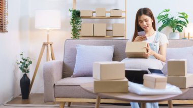 Online seller concept, Female entrepreneur use smartphone to take a picture parcel boxes to client.