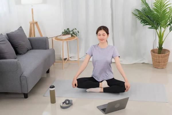 Yoga exercise concept, Young Asian woman with close eyes and meditation doing yoga training online.