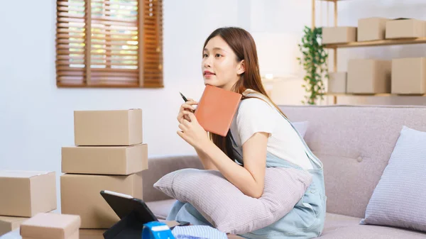 Online merchant concept, Female entrepreneur relaxes after packaging product into parcel boxes.