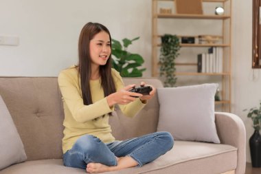 Relaxation concept, Young woman sitting on the couch to control joystick while playing video games.