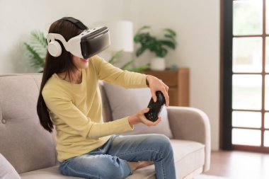 Relaxation concept, Young woman in VR glasses and controls the joystick to playing exciting games.