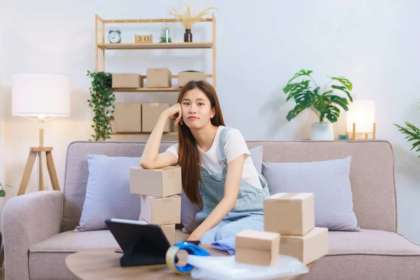 Online seller concept, Female entrepreneur feel exhausted after packing product in box for shipping.