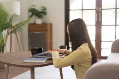 Leisure activity concept, Young woman typing on laptop while sitting to relaxation on the floor.