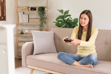 Concept of activity in home, Young woman sit on couch to playing video game with joystick console.