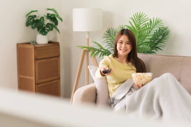 Concept of activity in home, Young woman lying on couch to changing channel and watch television.