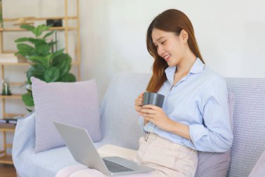 Business at home concept, Businesswoman reading marketing plan data on laptop and drinking coffee.
