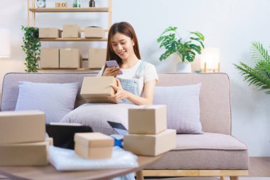 Online trader concept, Female entrepreneur use smartphone to take a picture parcel boxes to client.
