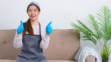 Housekeeping concept, Housemaid smile and doing thumbs up gesture after successfully cleaning house.