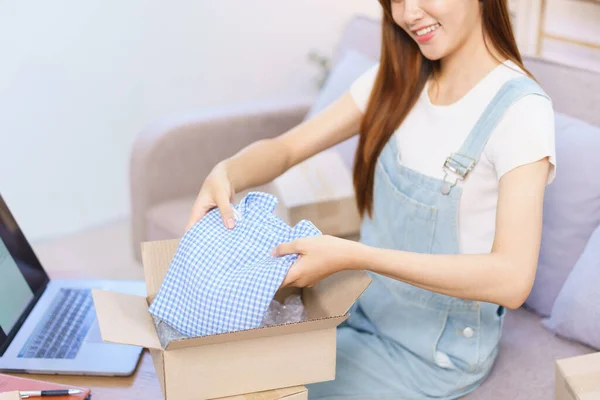 Online merchant concept, Female entrepreneur packing product into parcel box to prepare send client.