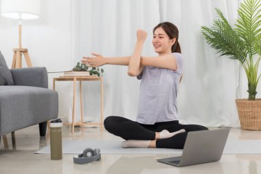 Yoga exercise concept, Young Asian woman stretching arms before workout with yoga training online.