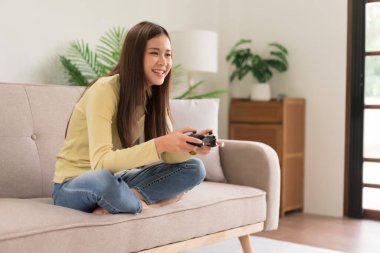 Concept of activity in home, Young woman sit on couch to control joystick while playing video game.