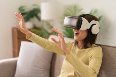 Concept of activity in home, Young woman touching the air to experience the virtual with glasses VR.
