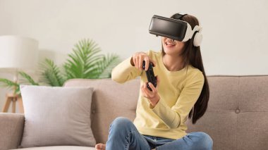 Eğlence aktiviteleri konsepti, VR gözlüklü genç bir kadın ve oyun oynamanın joystick 'ini kontrol ediyor.