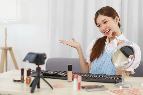 Beauty blogger concept, Young Asian woman recommend how to using cosmetics in live streaming.