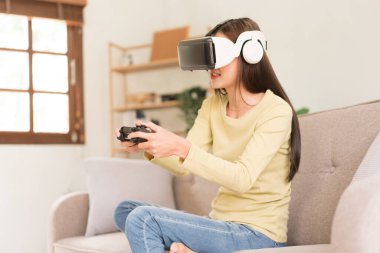 Concept of activity in home, Young woman having fun while playing game with VR glasses and joystick.