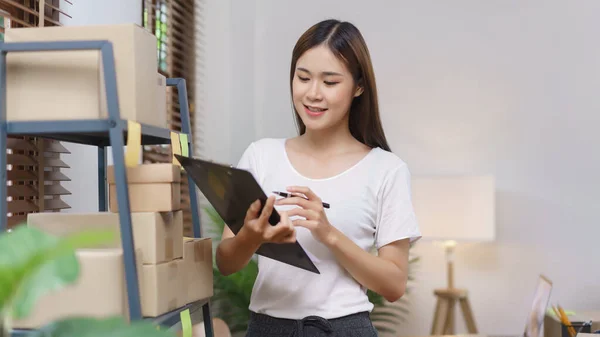 Online selling concept, Asian business women holding clipboard to checking products in store.