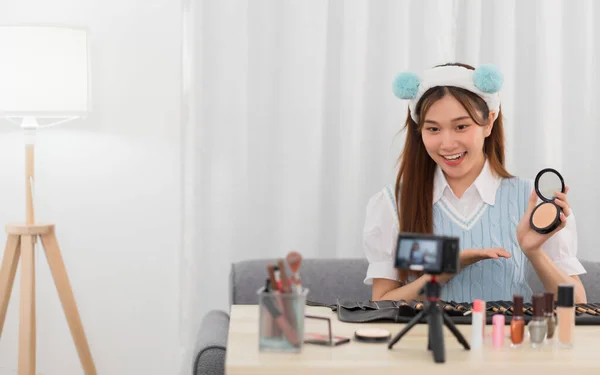 Beauty blogger concept, Asian woman is giving advice of powder to subscribers in live streaming.