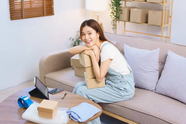 Online merchant concept, Female entrepreneur holds parcel boxes and smiling while looking at camera.