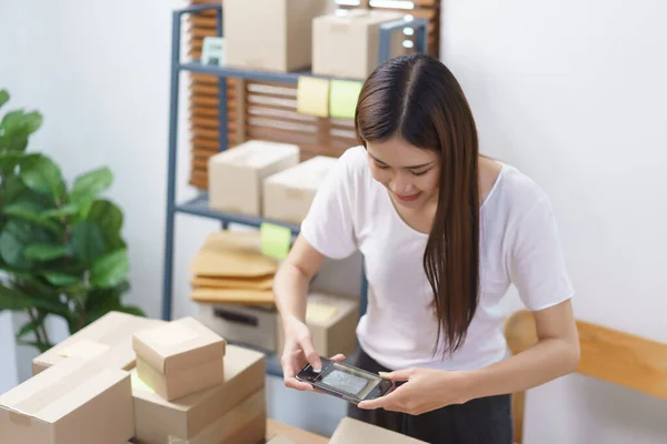 Online selling concept, Asian business women take a picture while packing product into parcel box.