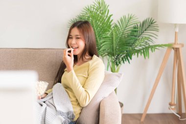 Boş zaman aktivitesi konsepti, patlamış mısır yiyen ve kanepede uzanmış film izleyen genç bir kadın..