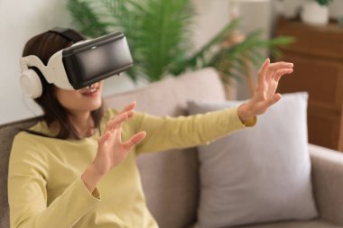 Concept of activity in home, Young woman touching the air to experience the virtual with glasses VR.