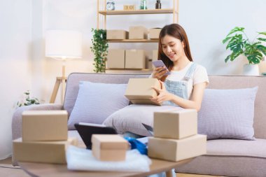 Online trader concept, Female entrepreneur use smartphone to take a picture parcel boxes to client.