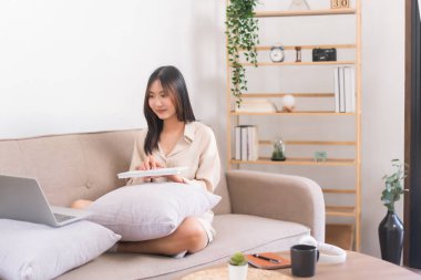 Oturma odasındaki aktivite kavramı, Asyalı kadın veri yazmak ve dizüstü bilgisayarda çalışmak için klavye kullanıyor.