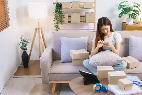 Online merchant concept, Female entrepreneur check online order on smartphone to prepare parcel box.