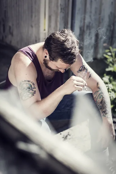 Exhausted rocker sits outside and smoke — Stock Photo, Image